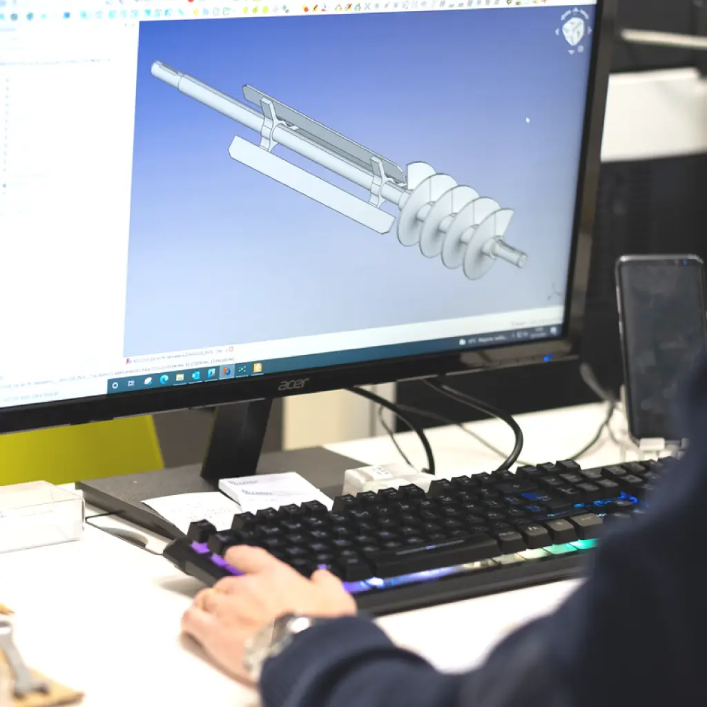 Pantalla mostrando modelo CAD de pieza industrial en oficina técnica